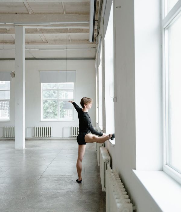 Woman performing a controlled, graceful movement in a bright, open space.